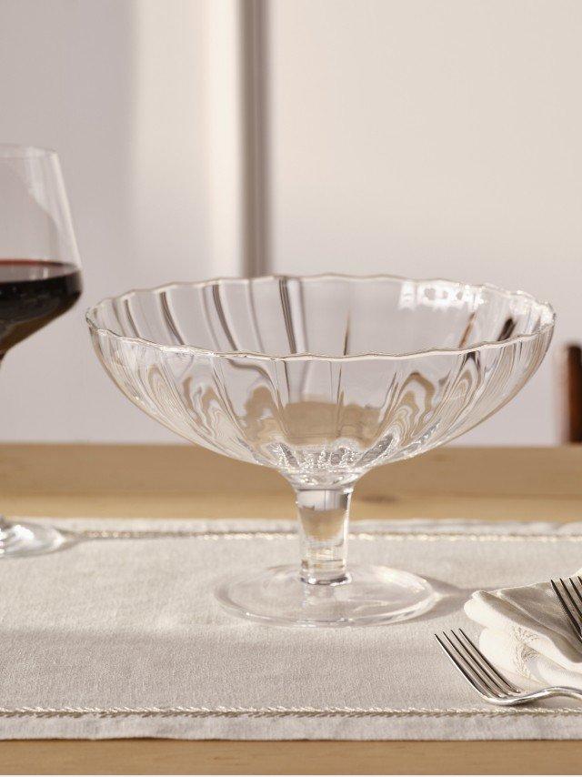 a glass bowl and a wine glass on a table with a fork and knife