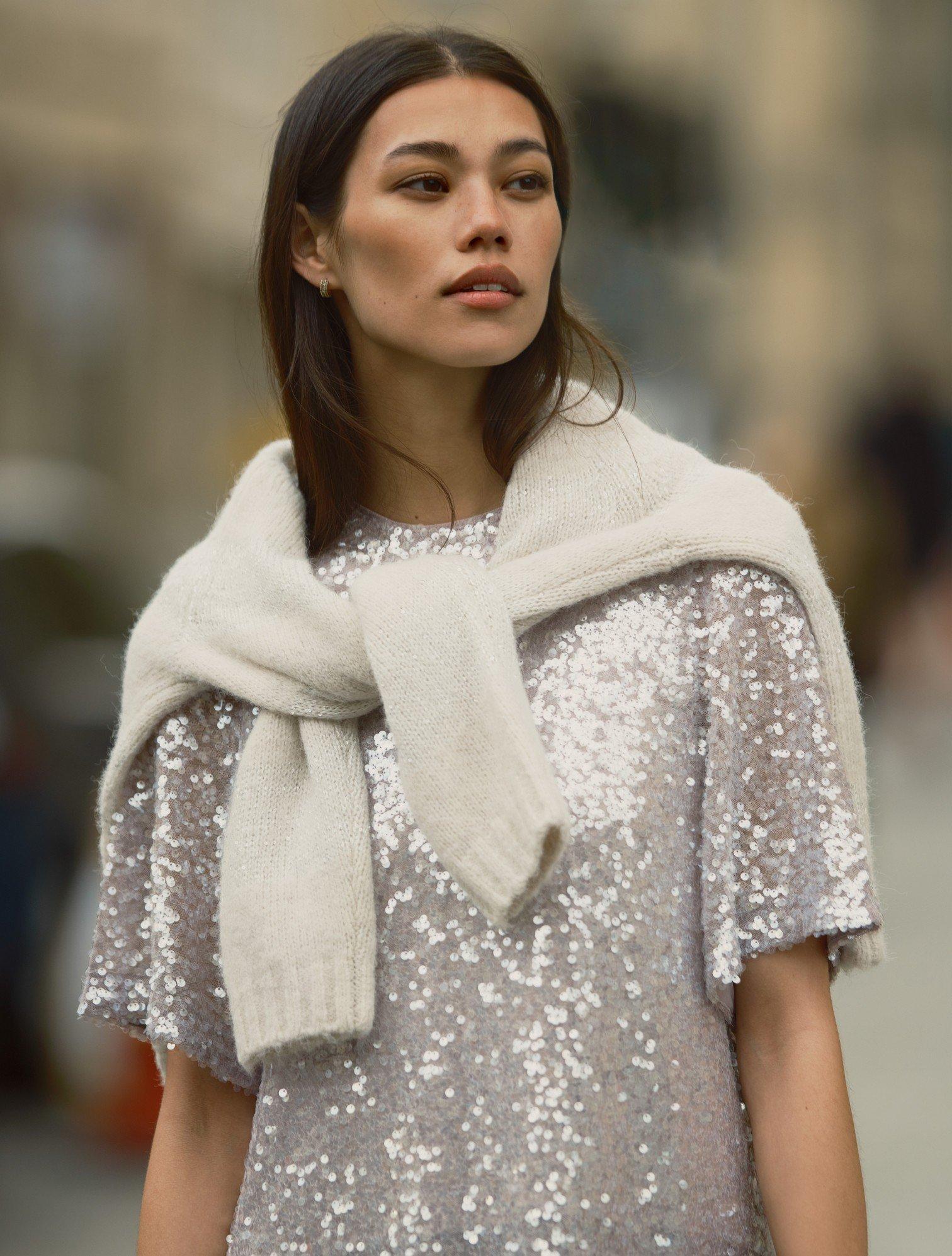 a woman in a sequined dress and scarf on the street