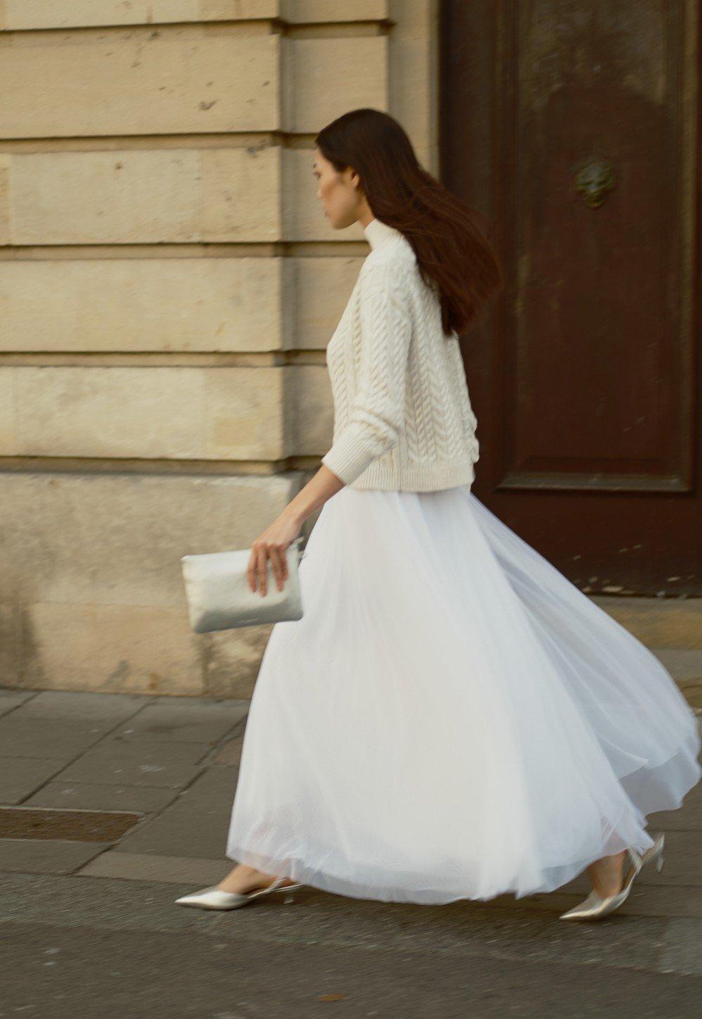 a woman in a white dress walking down the street