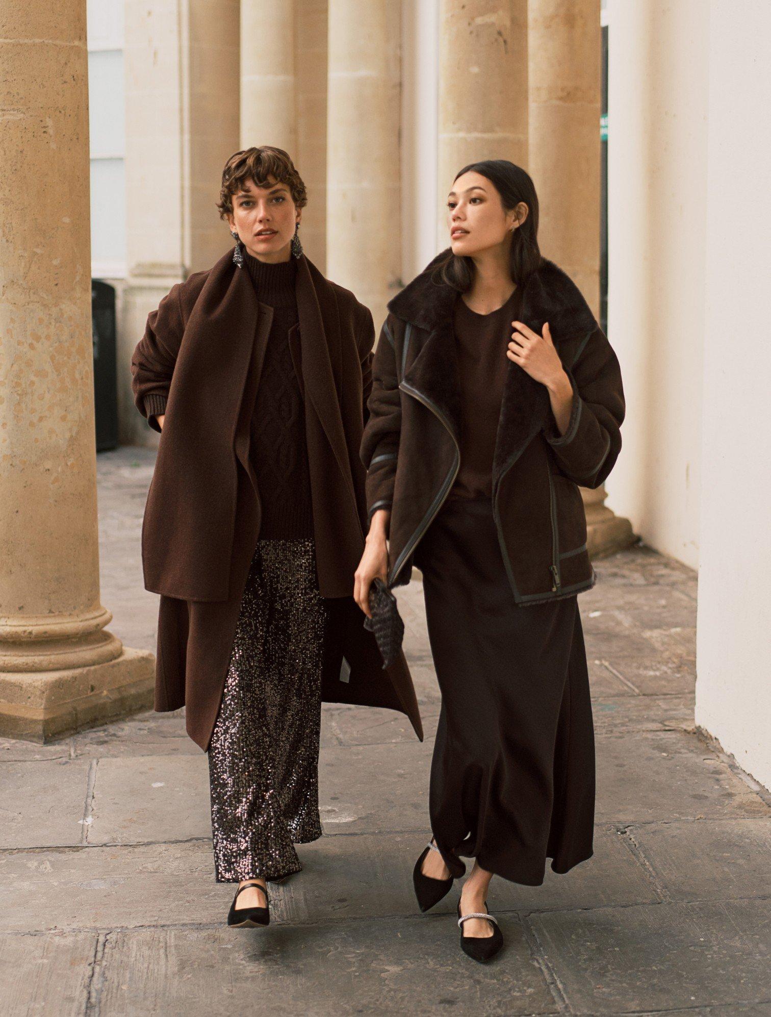 two women walking down a sidewalk in front of a building