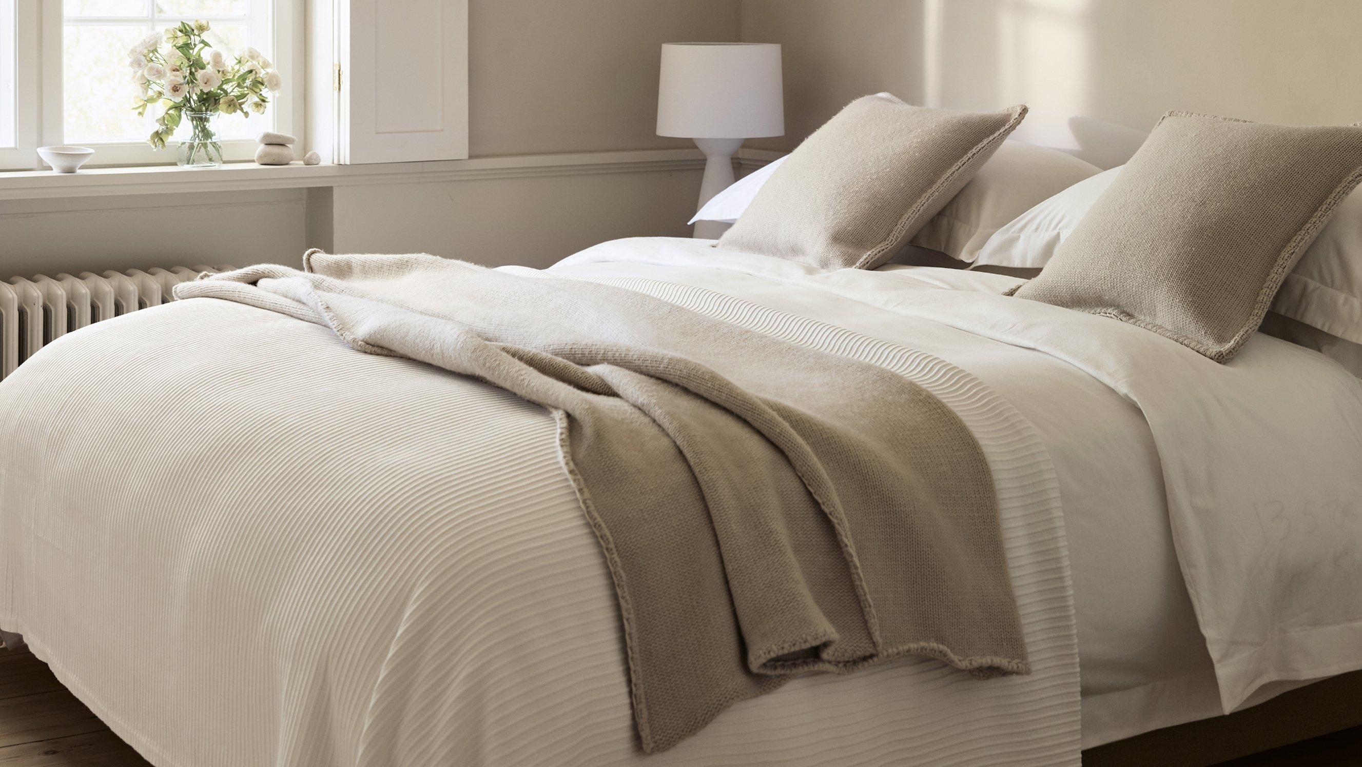 a bed with white sheets and pillows in a bedroom