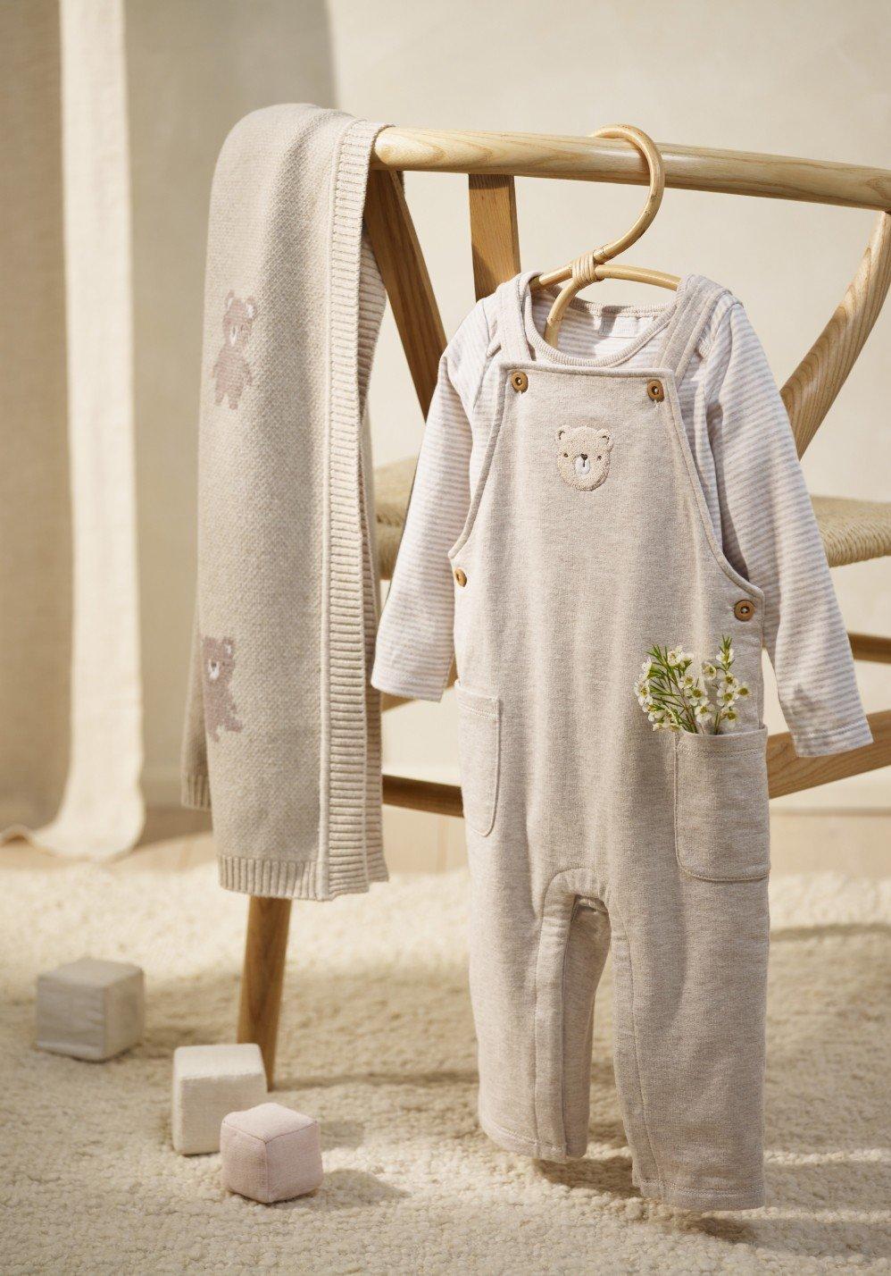 a baby's overalls and sweater are hanging on a chair