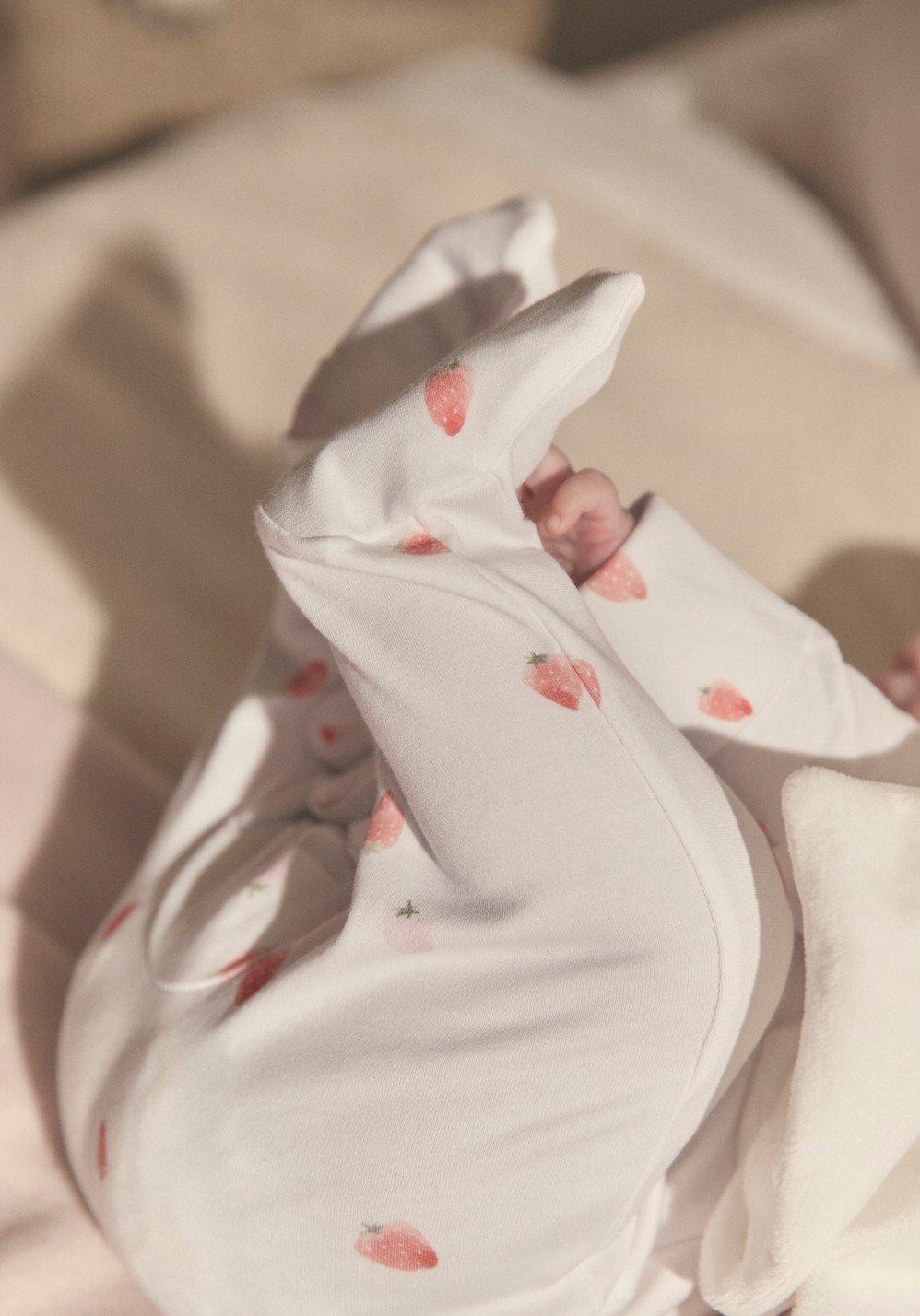 a baby in pajamas laying on a bed with a blanket