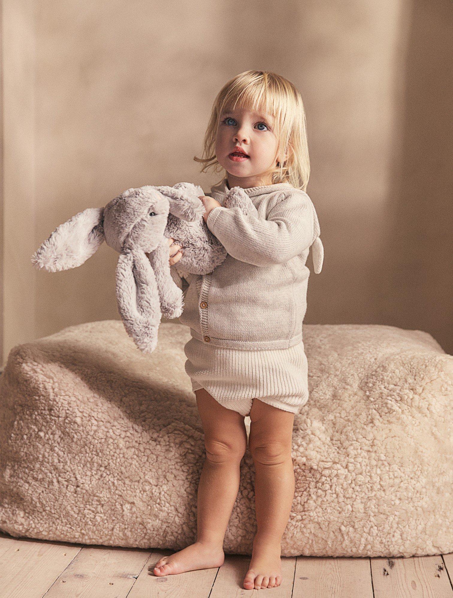 a baby in pink pajamas sitting on a bed