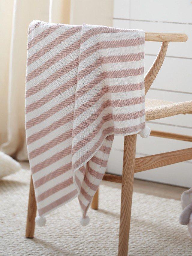 a pink blanket with white daisies on it is hanging on a crib