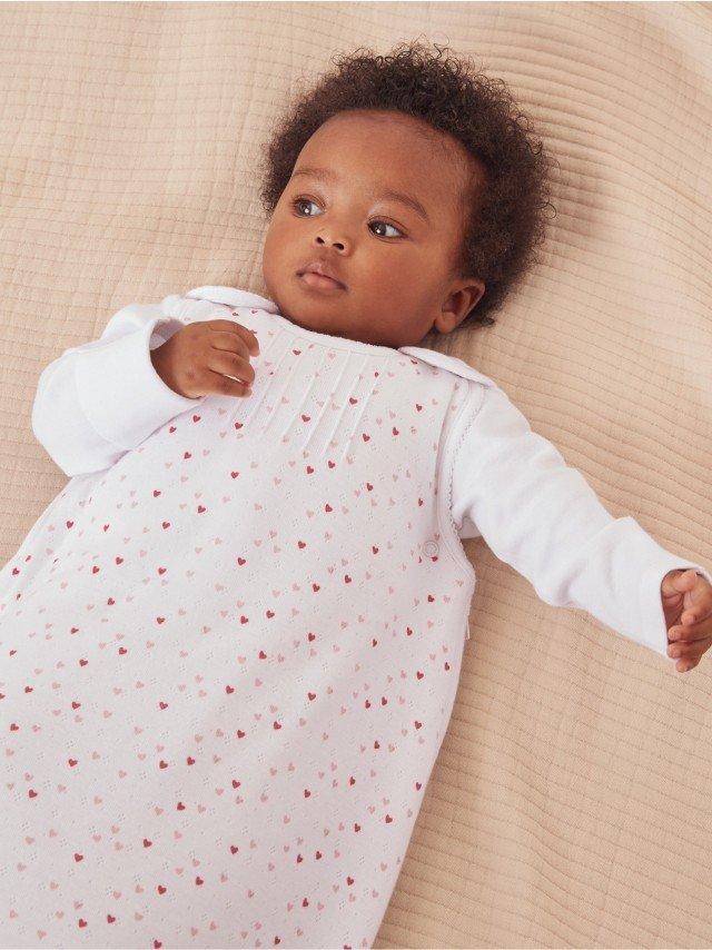 a baby laying on a bed with a white blanket