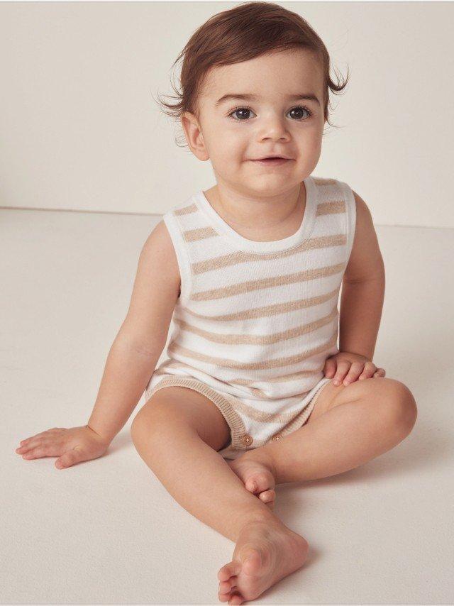 a baby sitting on the floor wearing a striped shirt