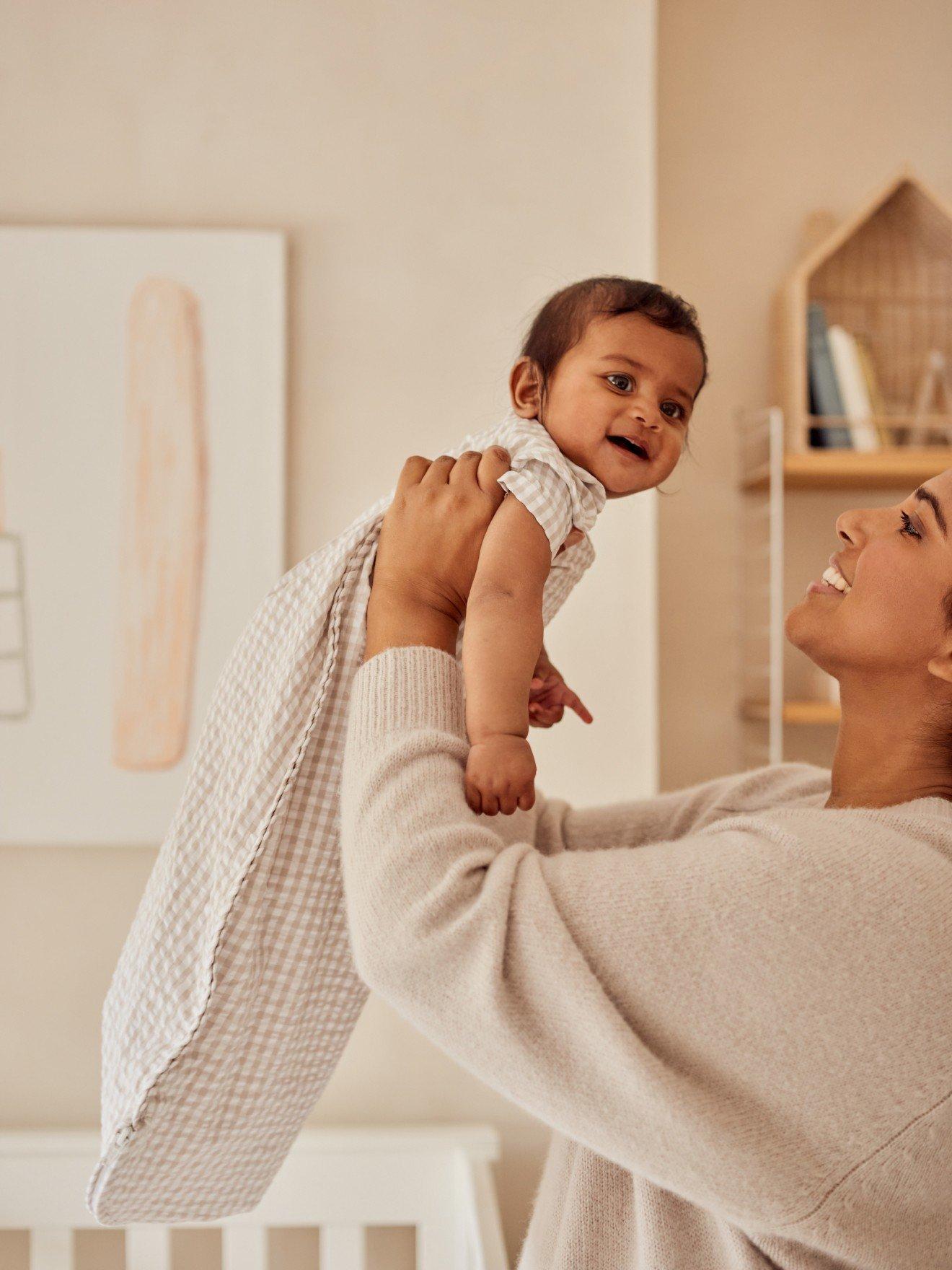 a woman holding a baby in her arms while standing in a room