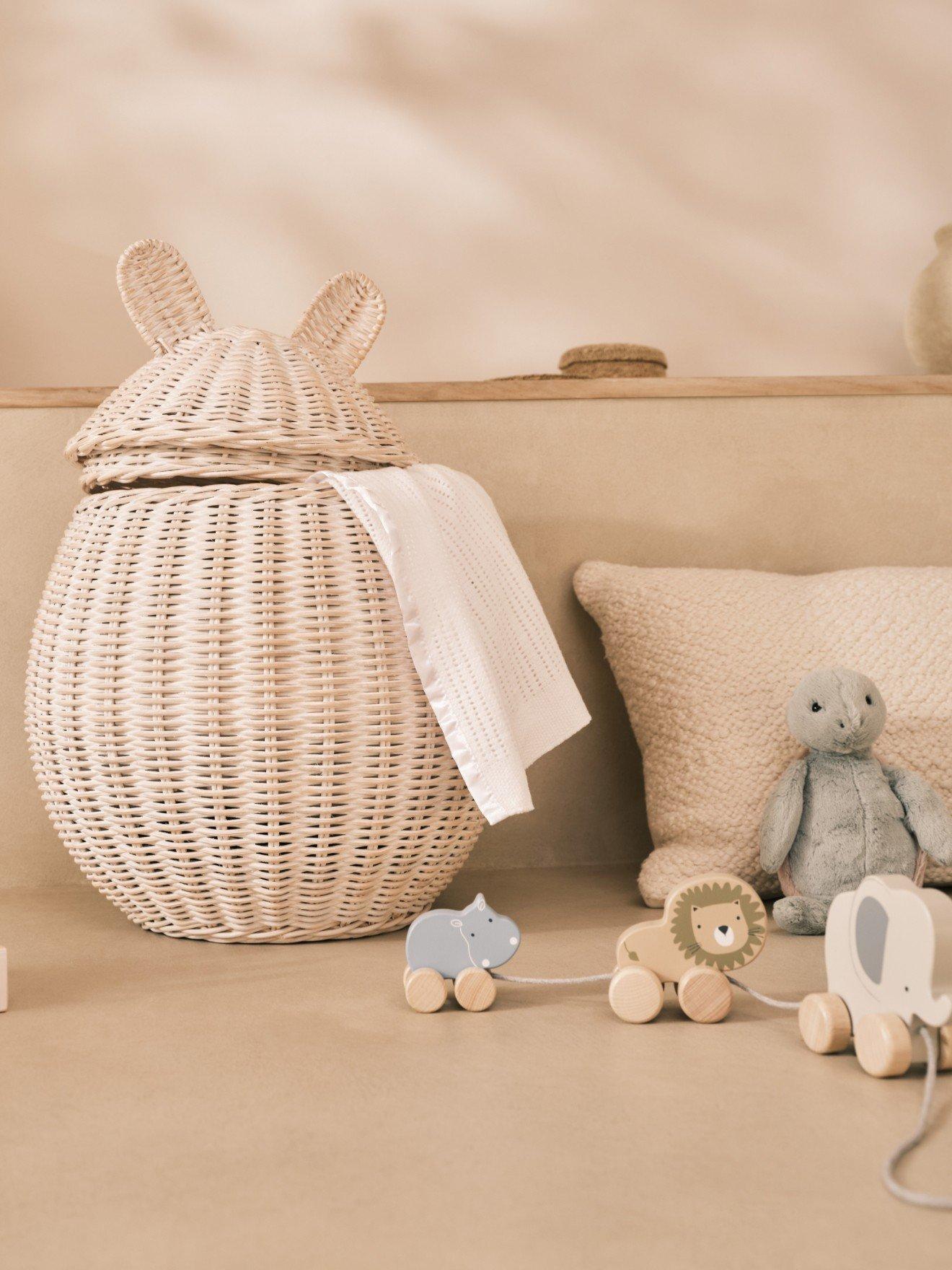 a white stuffed rabbit sitting on a bed next to a basket