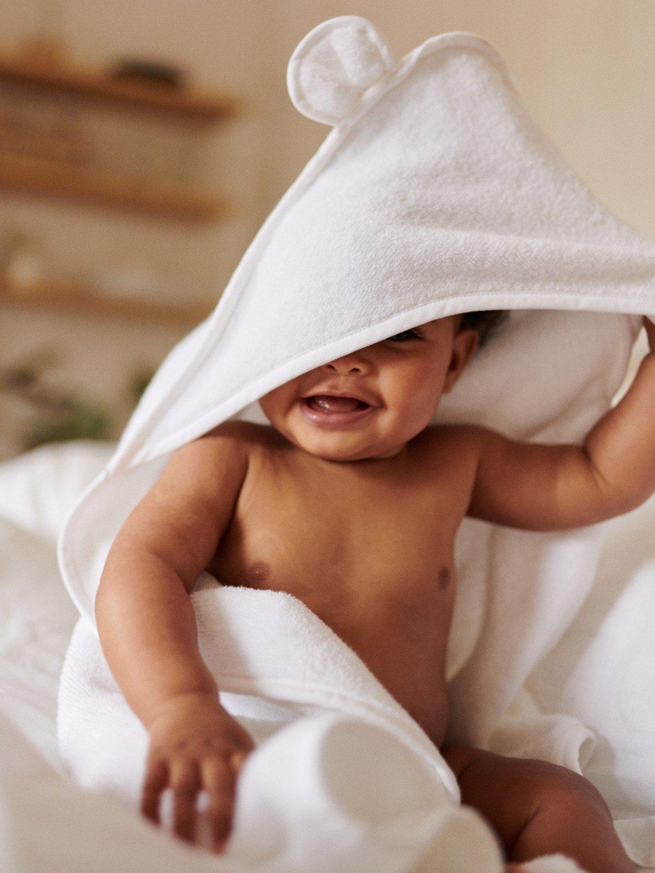 a woman holding a baby wrapped in a blanket with a hood