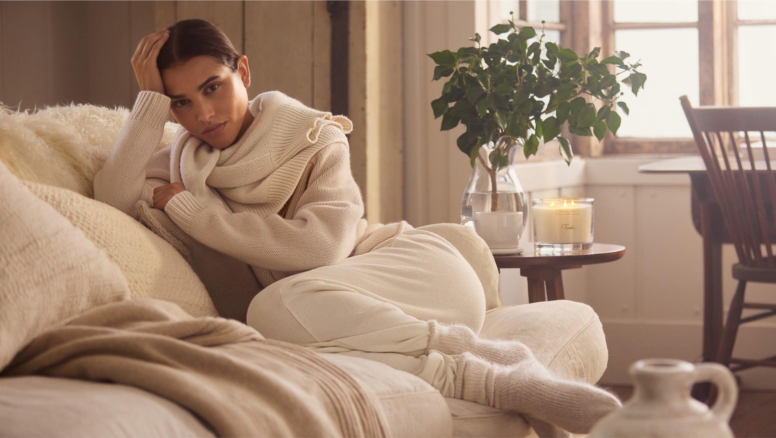 a woman in a white sweater sitting on a couch