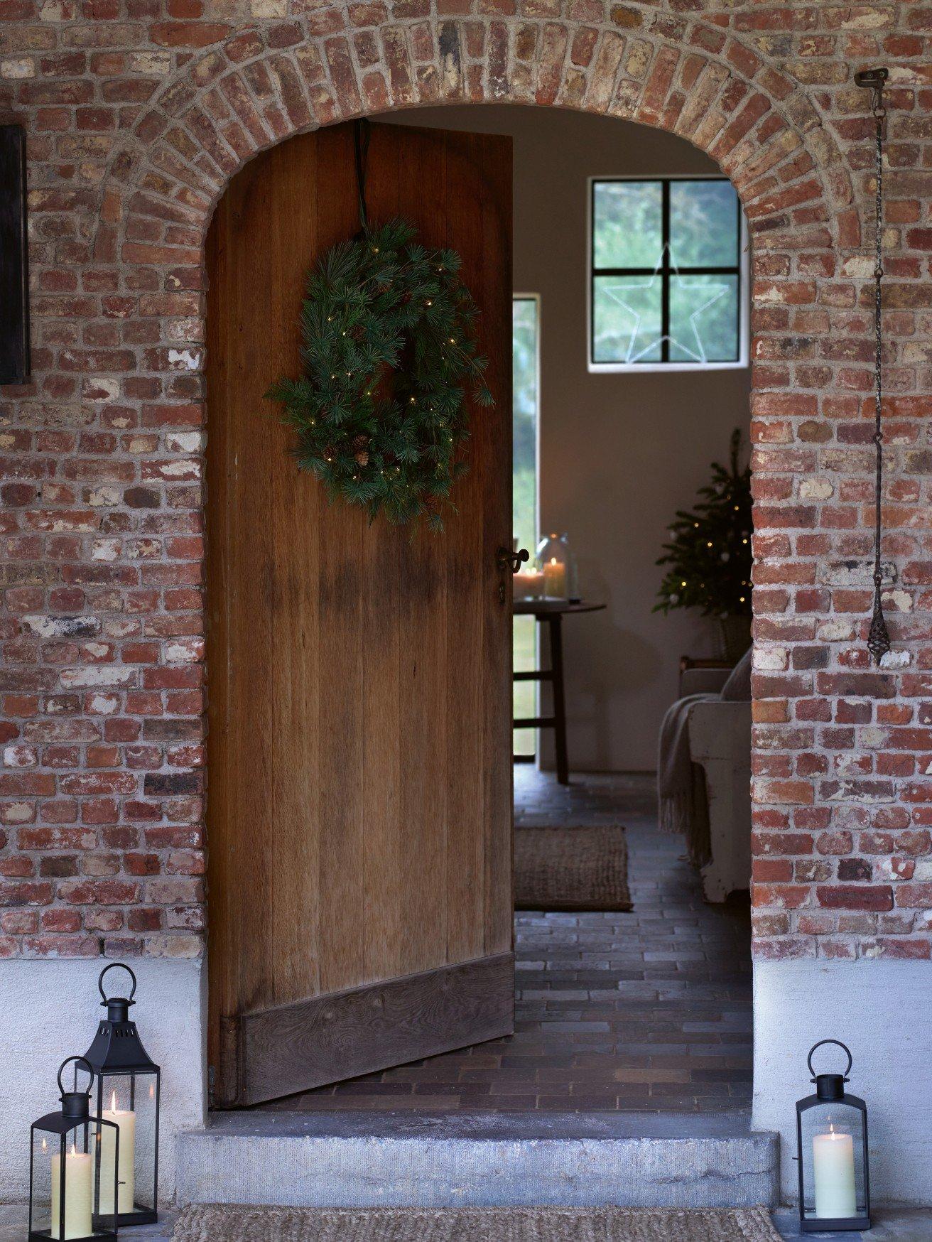 a door to a brick house with a wreath on the door