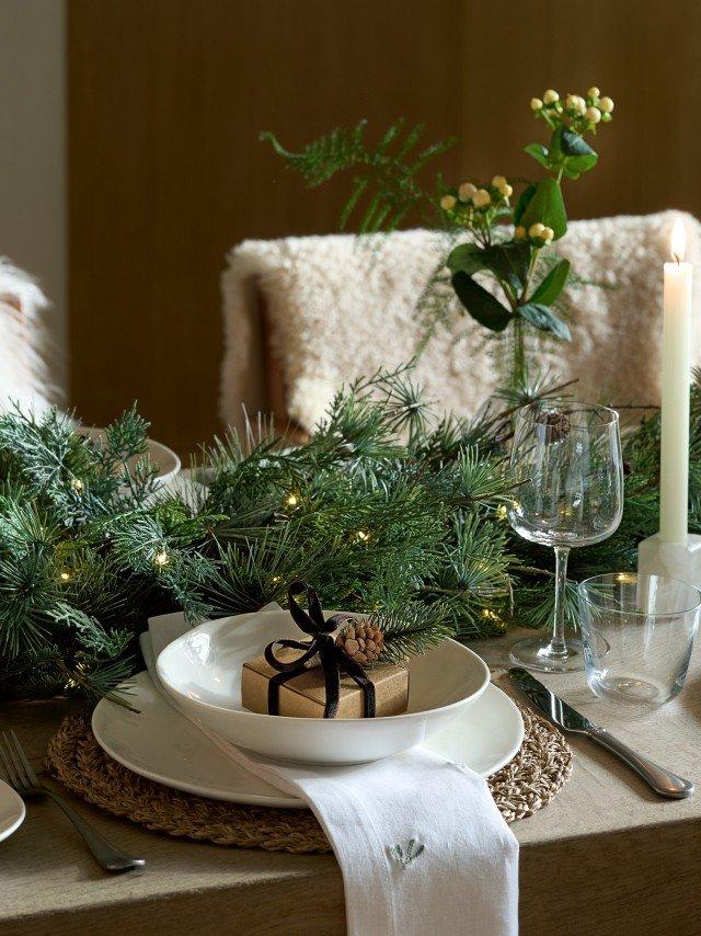 a table setting with a plate, napkin, candle and a gift