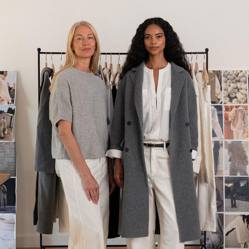 two women standing in front of a rack of clothes