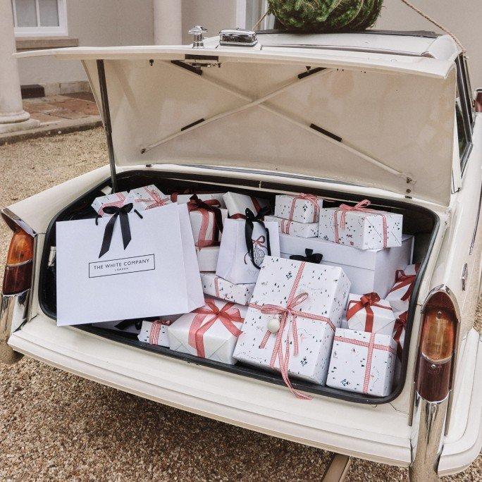 a white car with a trunk full of presents and wrapped boxes