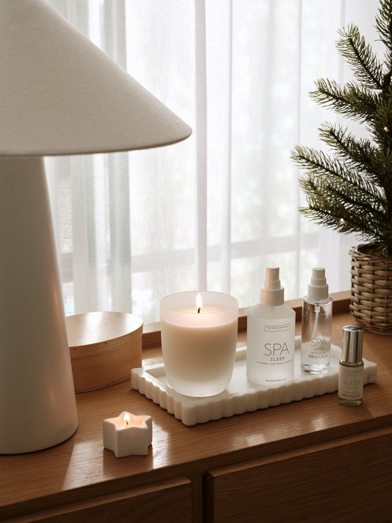 a table with a candle, a bottle of lotion, and a small plant