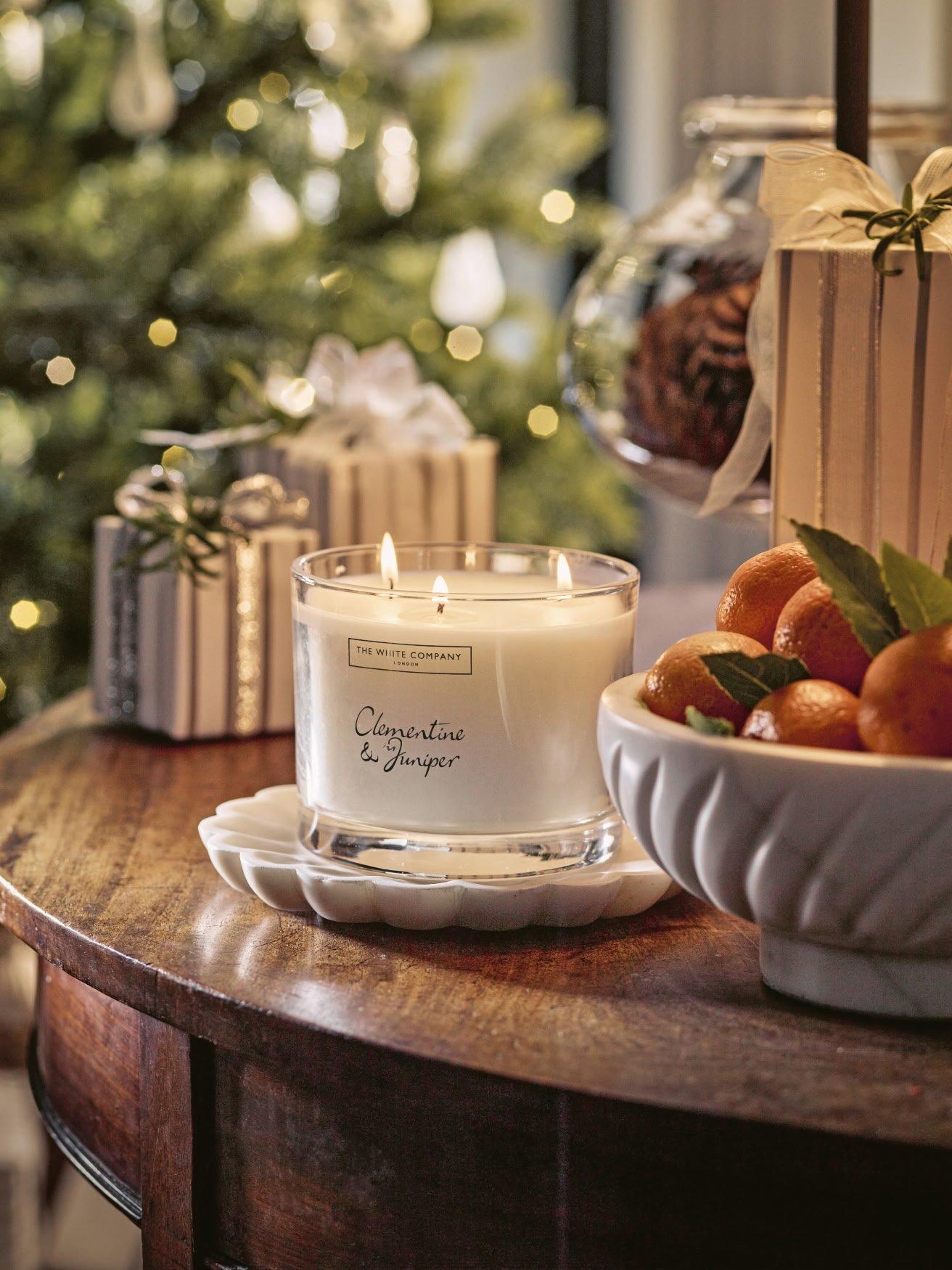 a table with a candle and oranges on it next to a christmas tree