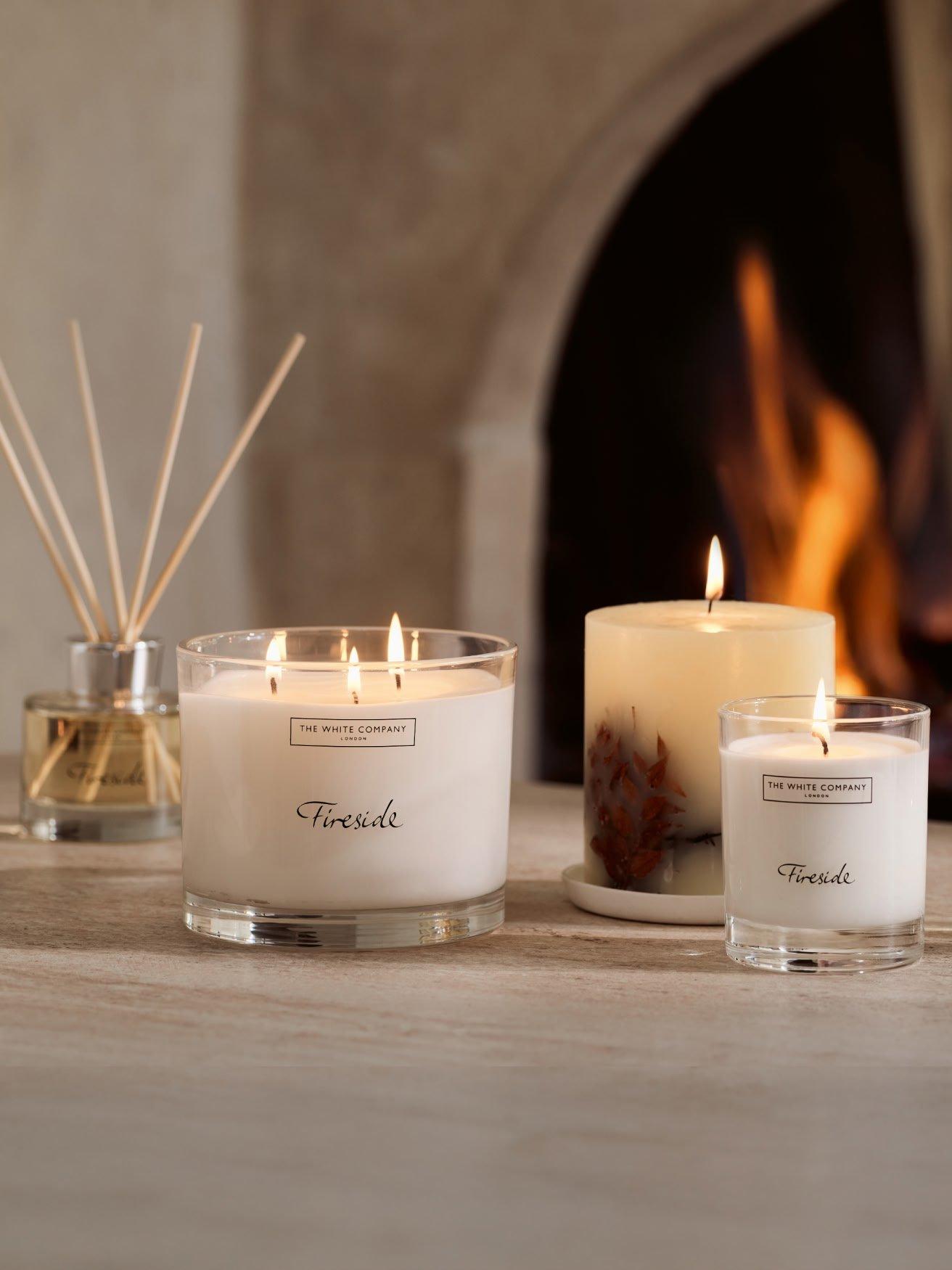 three candles are sitting on a table next to a fireplace