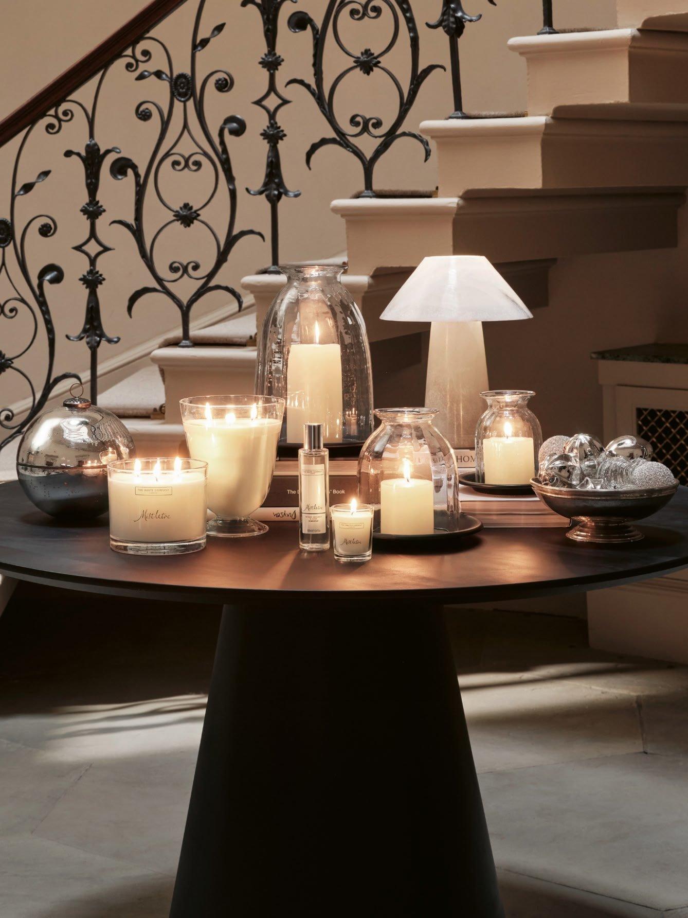 a table with candles and lamps on it in front of a staircase
