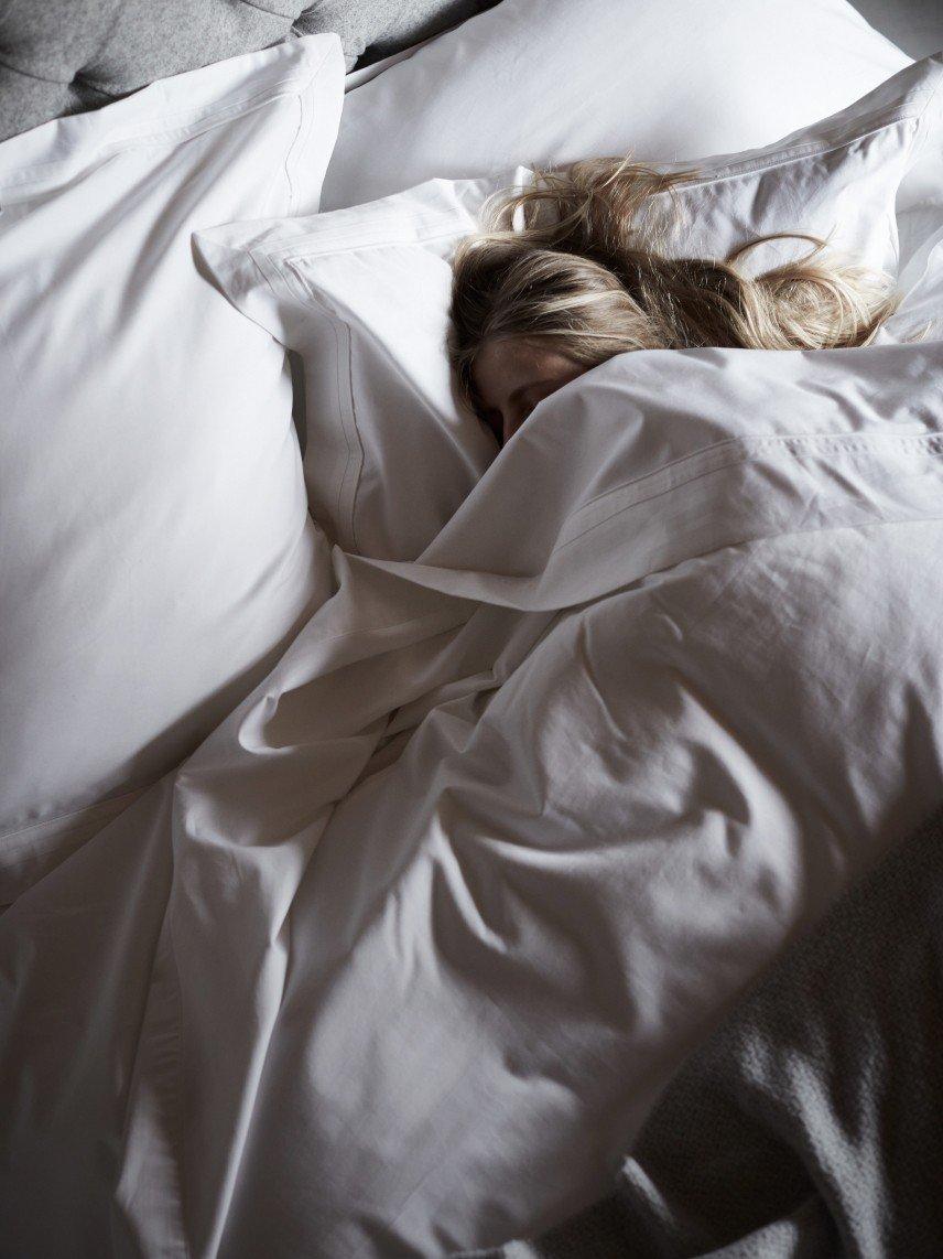 a woman sleeping in a bed with a white sheet