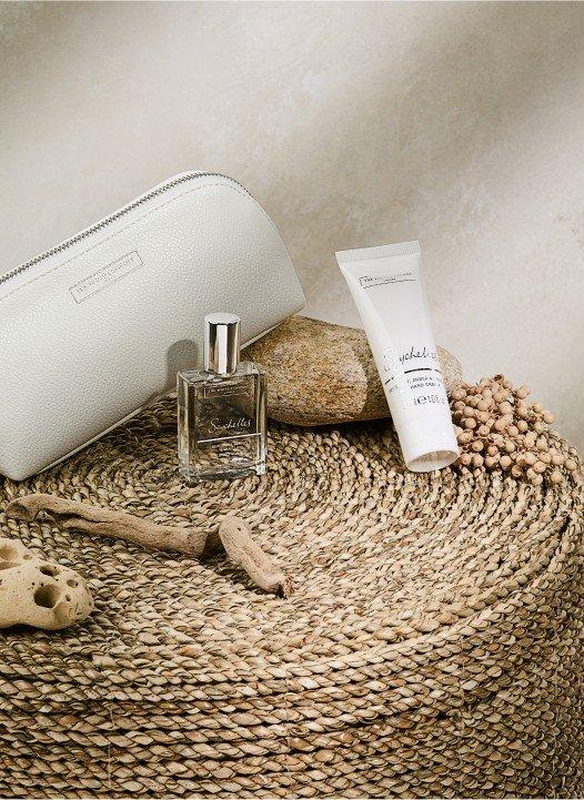 a white bottle of perfume sitting on top of a round wicker basket