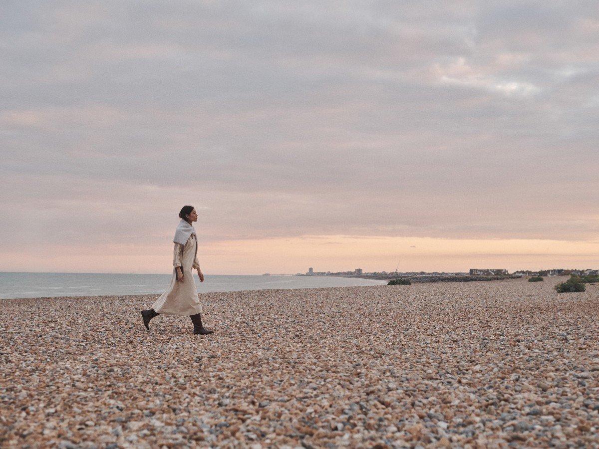 a man walking on a beach with a dog in his arms