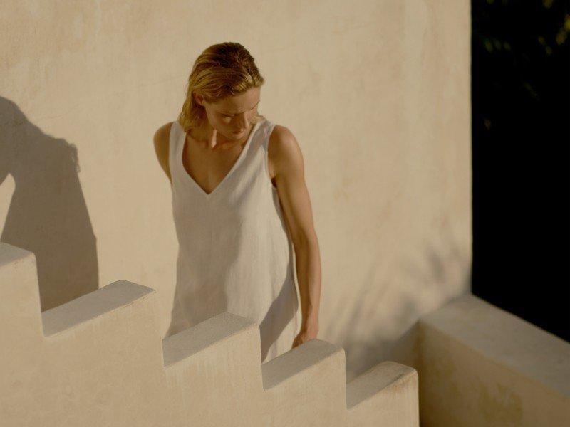 a woman in a white dress climbing down some stairs