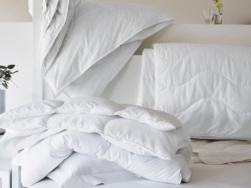 a bed with a pile of white sheets and pillows