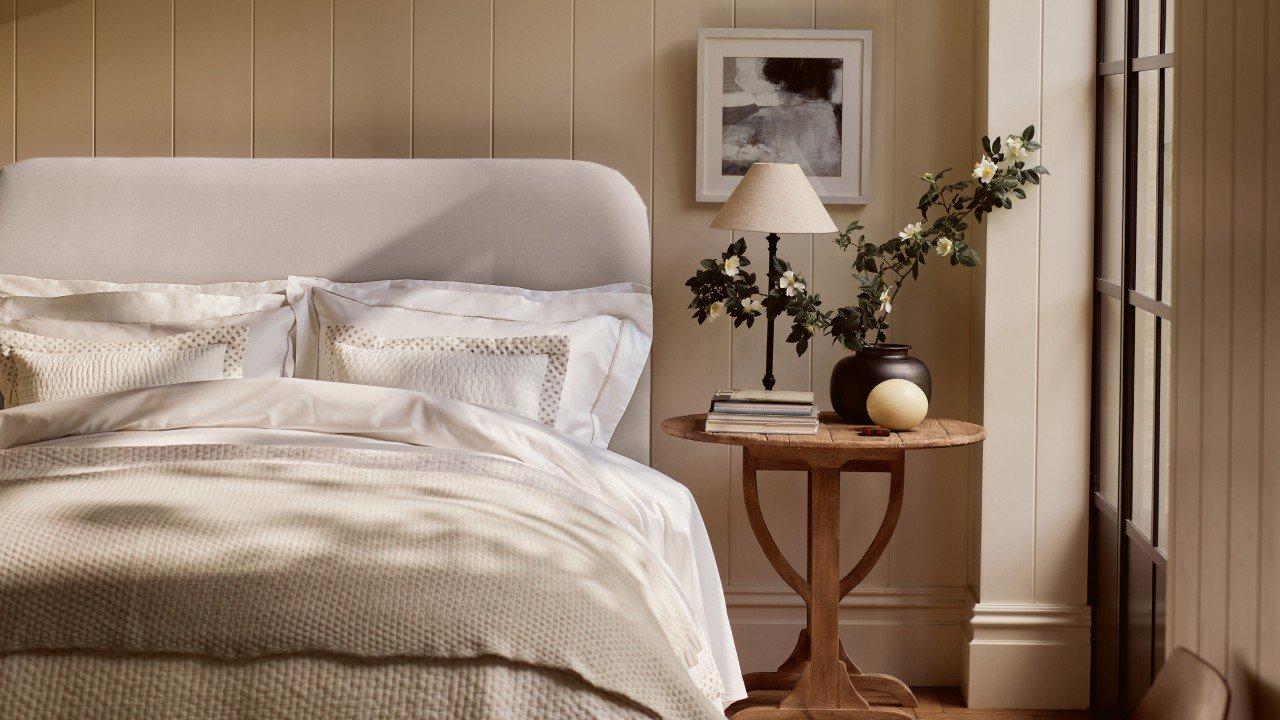 a bed with white sheets and pillows in a bedroom