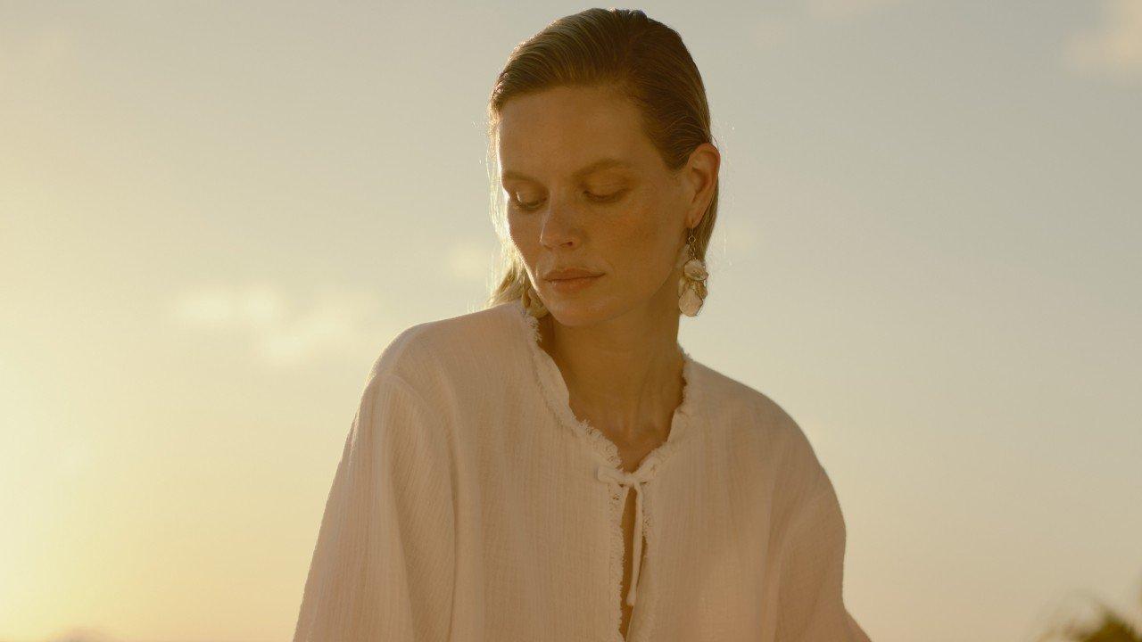 a woman in a white sweater dancing on the beach