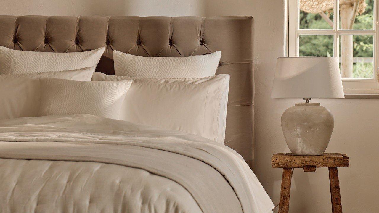 a bed with a white comforter and pillows in a bedroom