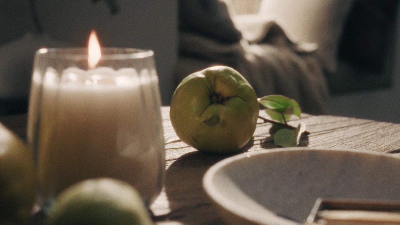 a candle on a table with a plate of fruit and a candle