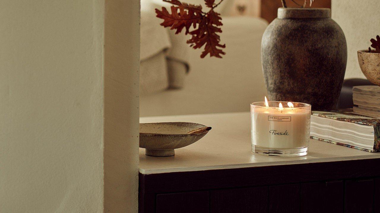 a candle on a table next to a bowl and a vase