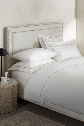 a bed with a white comforter and pillows with a plant