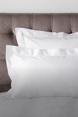 two pillows on a bed with a white sheet and a white pillow