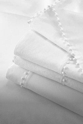 a bed with white sheets and pillows on a white bed