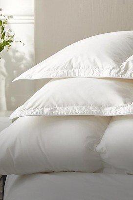 a bed with white sheets and pillows in a bedroom