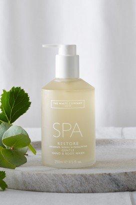 a bottle of spa lotion sitting next to some green leaves