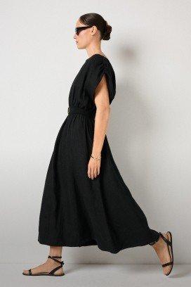 a woman in black dress and sandals walking