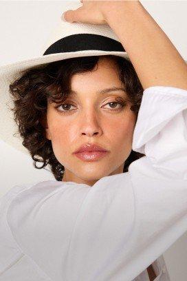 a woman in a white shirt and a baseball cap posing for a picture