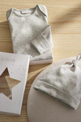 a baby's hat, shirt and book are laid out on a table