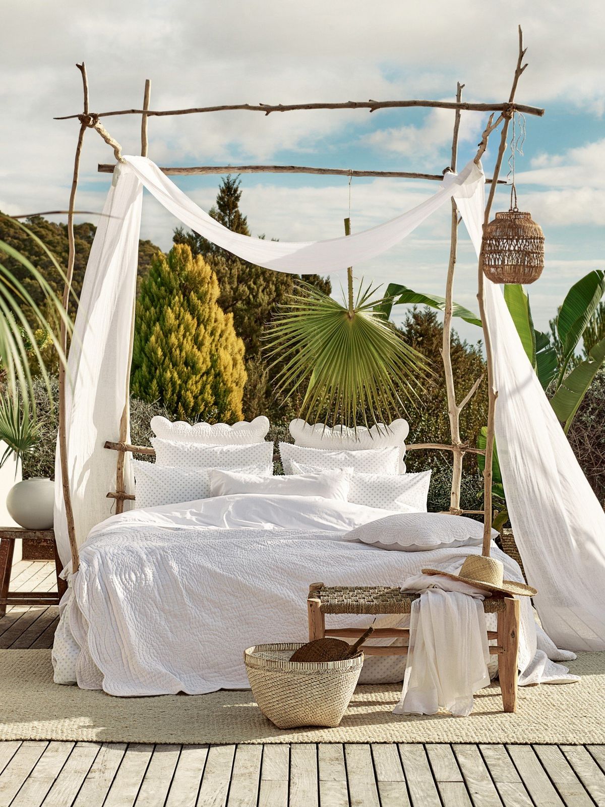 a bed with white sheets and a canopy on a wooden deck