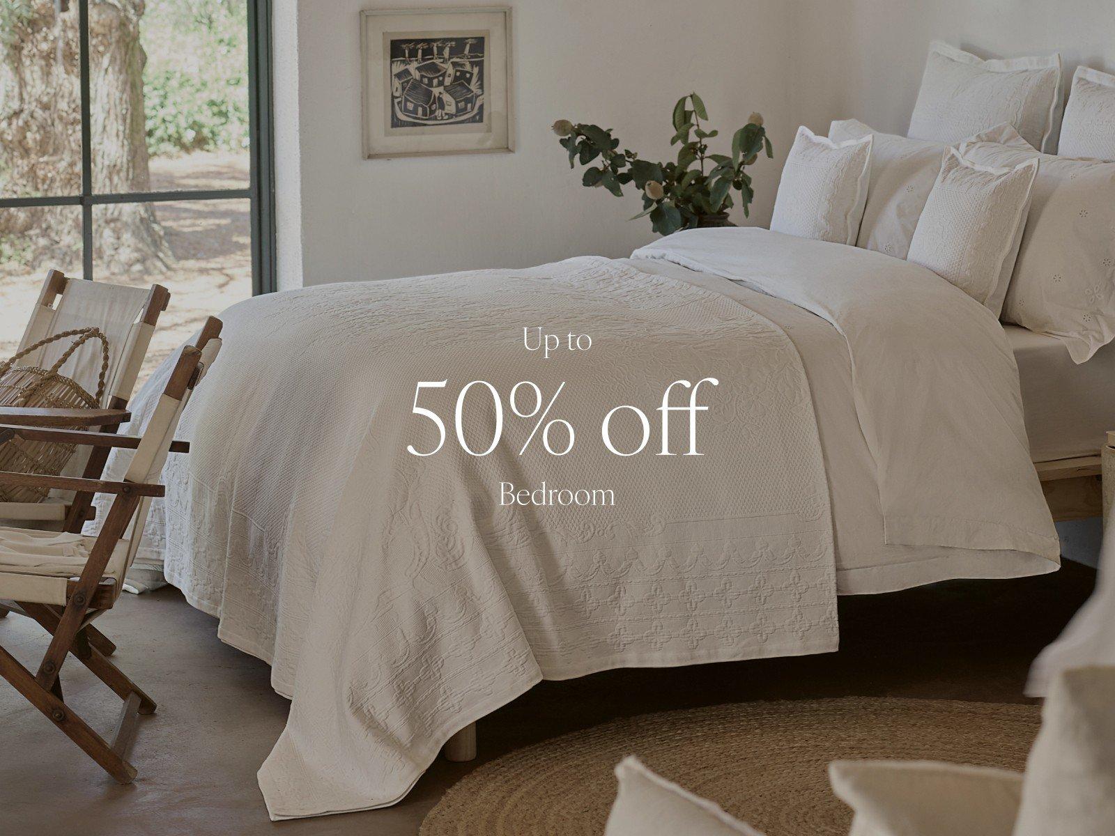 a bedroom with a bed and chair in it and a 50% off sign