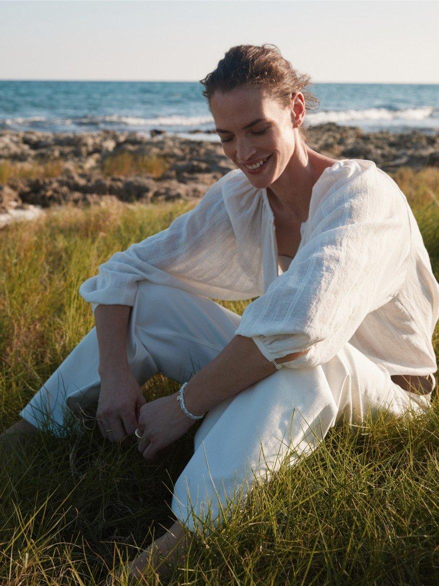 a woman in white overalls laying on a rock