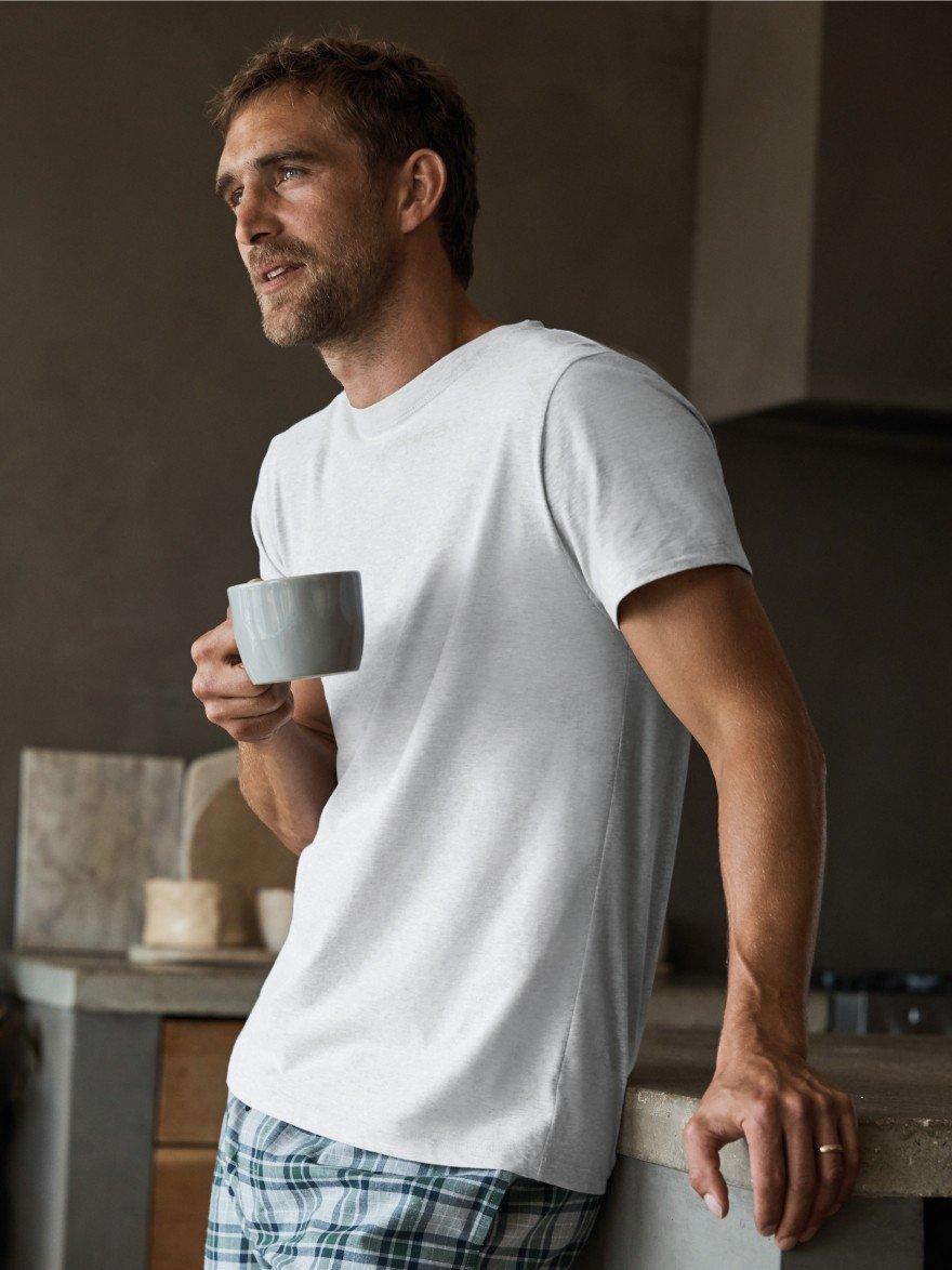 a man standing in pyjamas with a mug