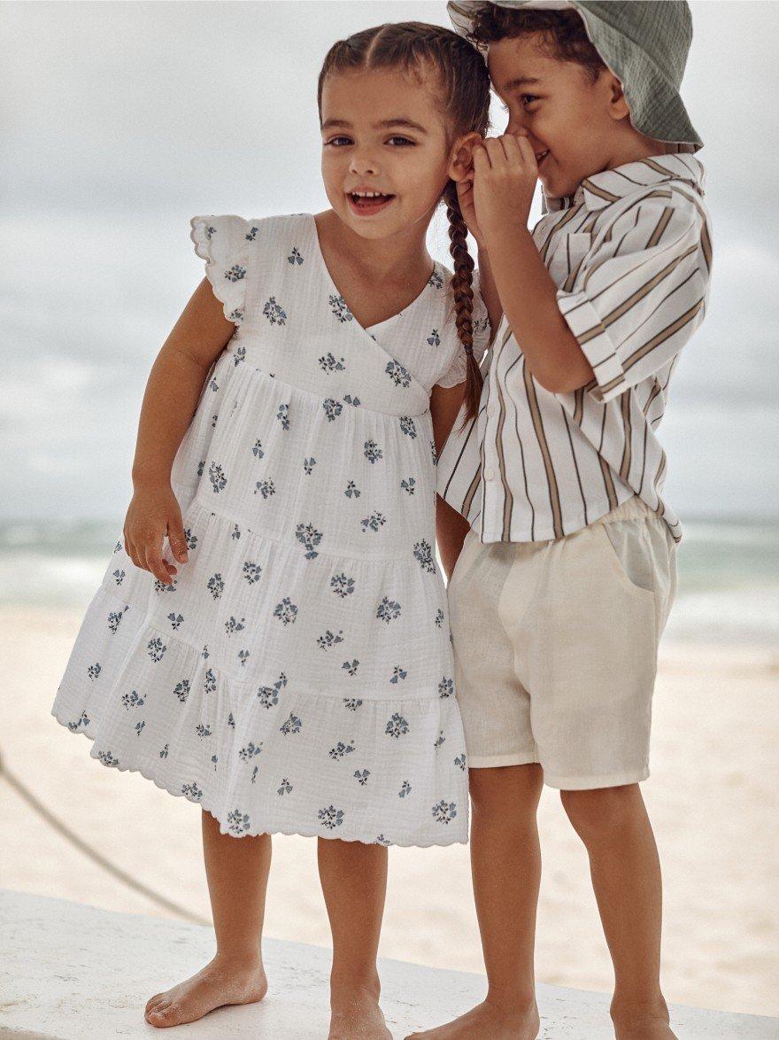 two children standing in the sand smiling