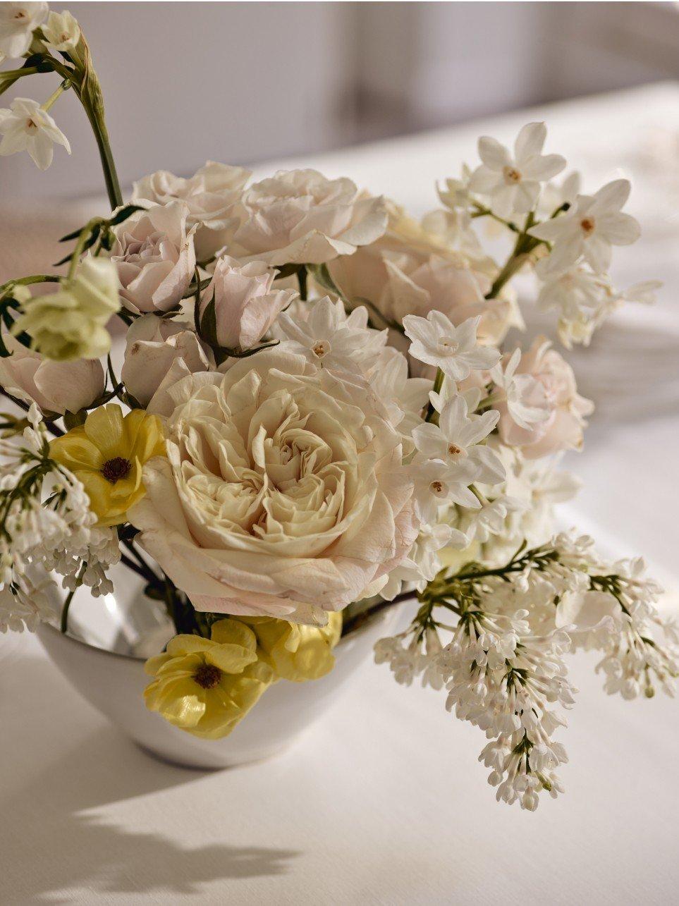 a white and yellow flowers in a vase on a table