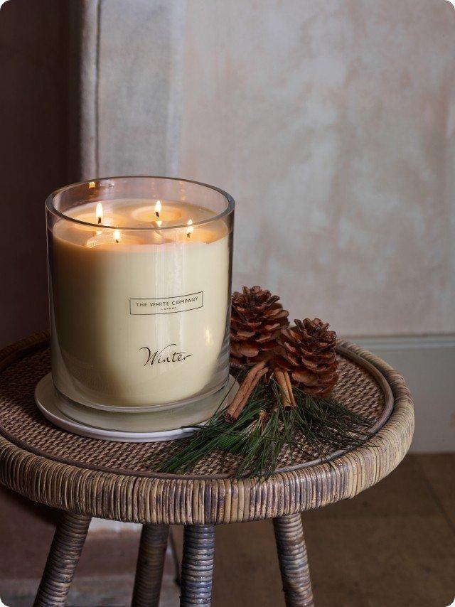 a candle sits on a table with a pine cone and a candle holder