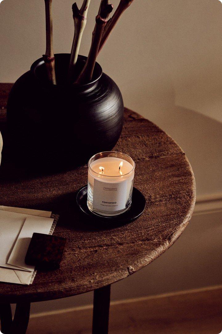 a candle on a table next to a vase of flowers