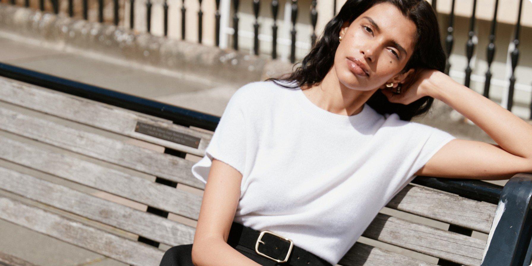 a woman in a white shirt sitting on a bench